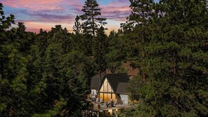 A cabin with a balcony, surrounded by dense forest. - Luxury A-Frame at Bear Mtn | Hot tub and game room (Big Bear Lake)