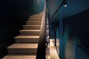 Uma escadaria com corrimão e luminária na parede.