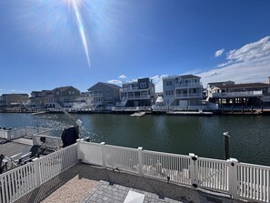 A waterfront property with a dock, a white fence, and a row of houses with balconies. - Waterfront Family Retreat with Dock, Kayaks & Beach Passes! (Stafford Township)
