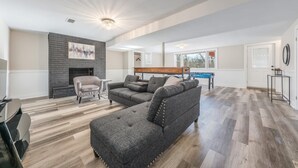 Amplia sala de estar con sofá modular, chimenea y una lámpara moderna.