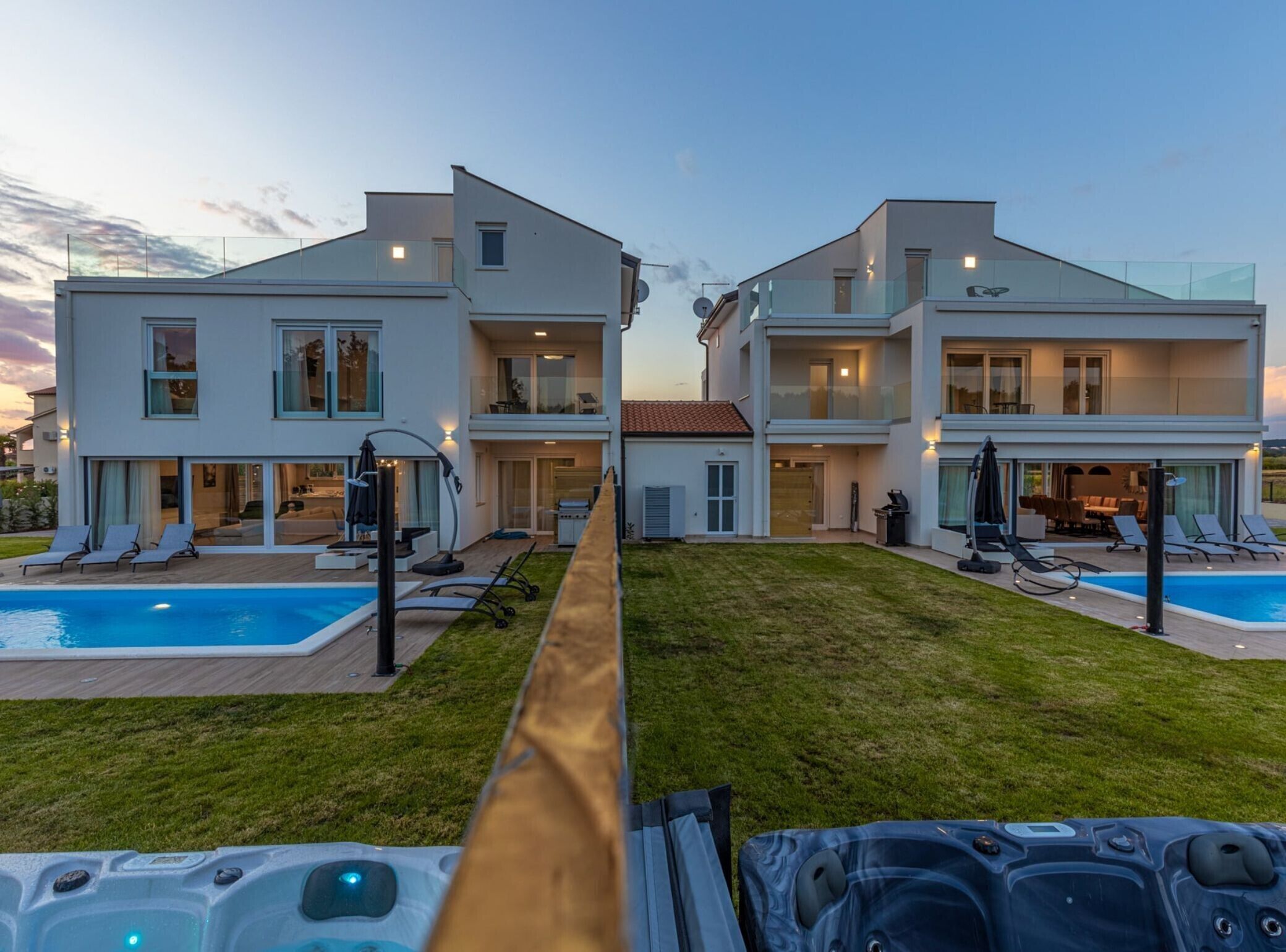 A modern two-story house with a swimming pool, outdoor seating, and a hot tub.