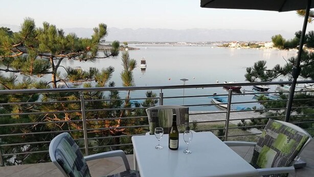 Eine Terrasse mit Tisch und Stühlen mit Blick auf ein Gewässer und einen Yachthafen.