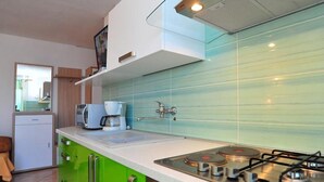 Eine moderne Küche mit einer grünen Arbeitsplatte, Edelstahlgeräten und einer gefliesten Spritzschutzwand.