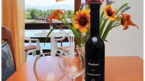 A table with a bottle of wine, a glass, and a vase with flowers.