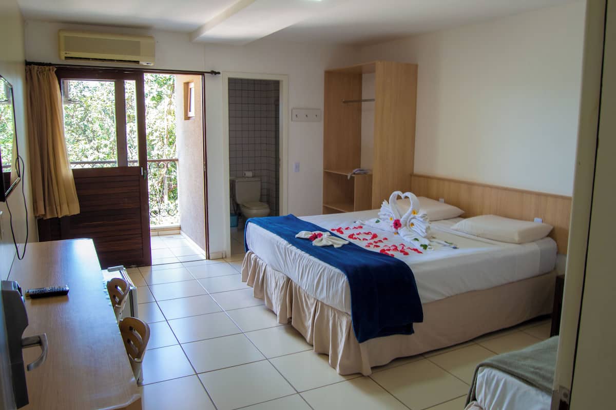 A hotel room with a bed, a desk, and a balcony.