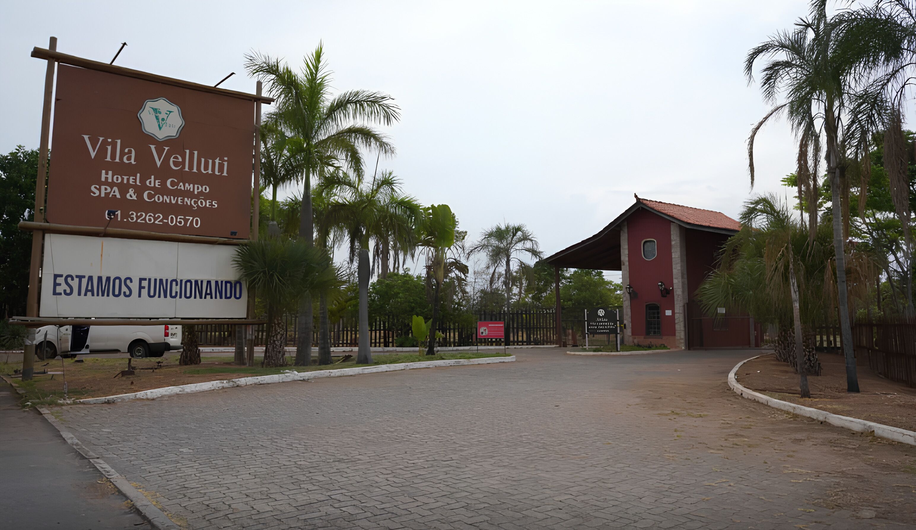 Le Vila Velutti Hotel de Campo se distingue par son entrée pavée, ses palmiers et son bâtiment rouge qui se dresse à l’arrière-plan.