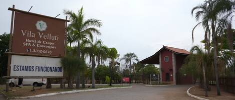 Le Vila Velutti Hotel de Campo se distingue par son entrée pavée, ses palmiers et son bâtiment rouge qui se dresse à l’arrière-plan.