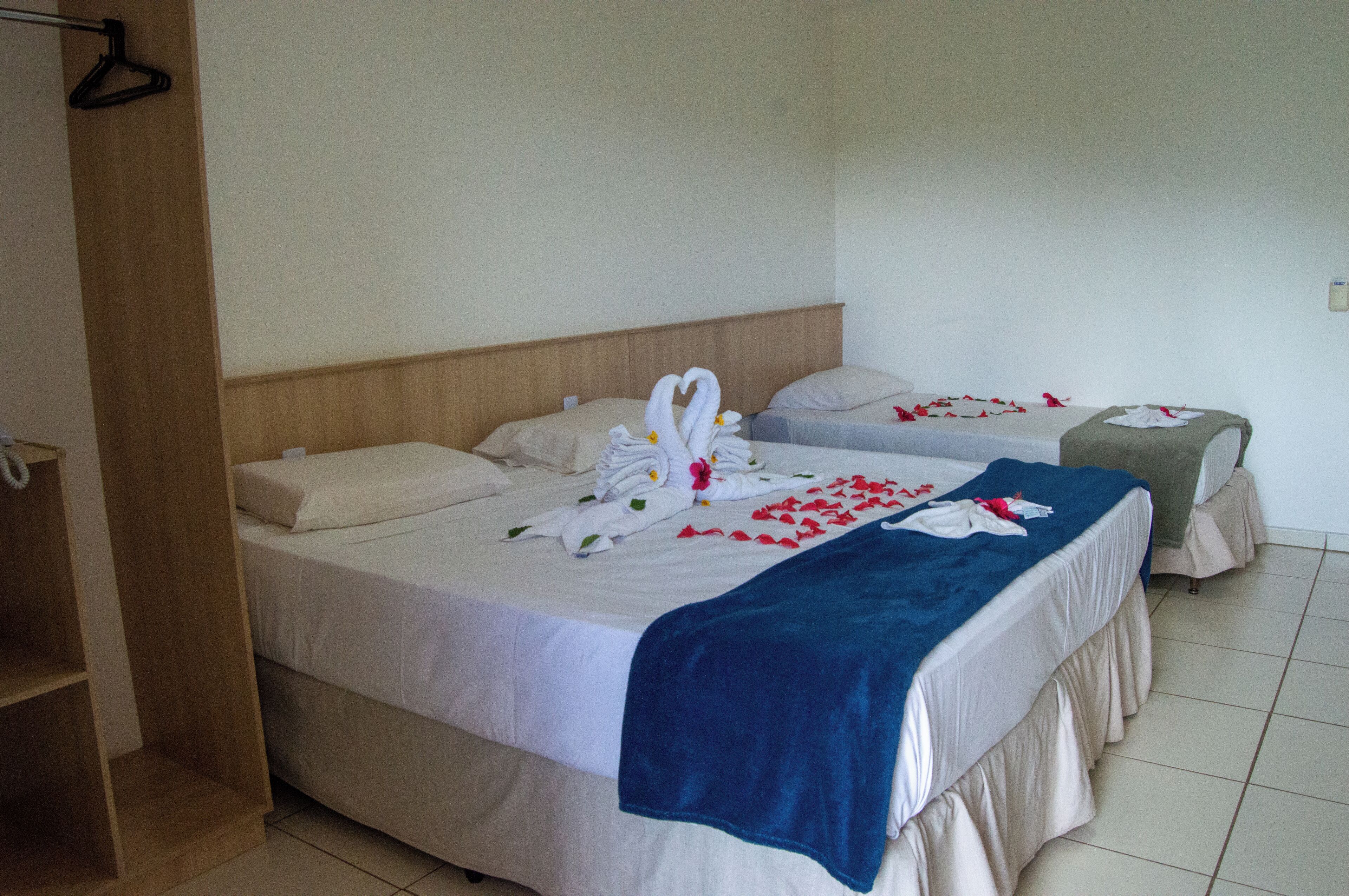 Ein Hotelzimmer mit zwei Betten, einem Holzschrank und einem kleinen Tisch.