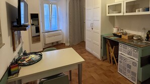 A compact kitchen with a dining table, chairs, a built-in oven, and a window with curtains. - In the Beautiful Middle of Pisa (Pisa)