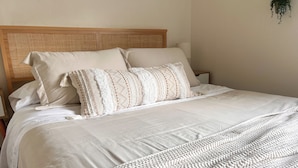 A neatly made bed with a wooden headboard, white bedding, and a knitted throw blanket. - The Hikers Haven  (Thompson Falls)
