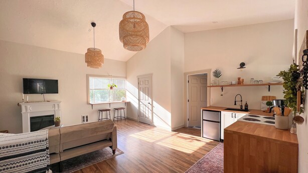 A spacious living room with a fireplace, a dining area, and a kitchen with wooden countertops and a sink. - The Hikers Haven  (Thompson Falls)
