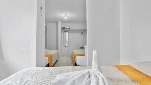 Une chambre d’hôtel avec deux lits, une petite salle de bain et un miroir.