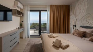 Una habitación de hotel moderna con cama, televisor, escritorio y balcón con vistas.