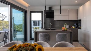 Una cocina moderna con una isla central, un comedor con sillas y vistas al exterior.