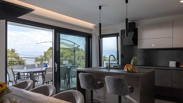 Una cocina moderna con una isla central, taburetes de bar y vistas al exterior.