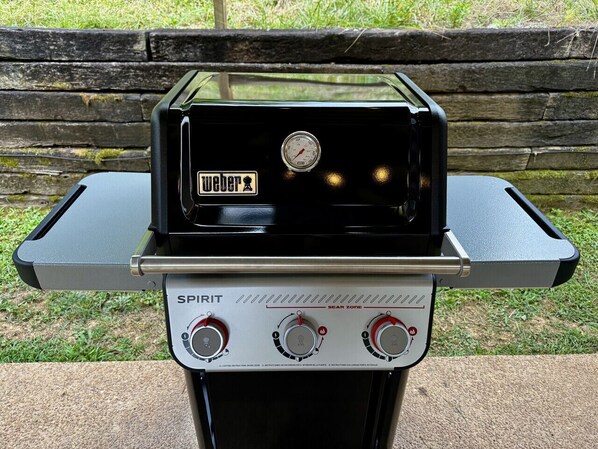 A Weber Spirit grill with a digital thermometer and control knobs.