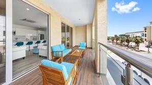 Un balcón con mobiliario de madera, una zona de cocina y vista a la calle.