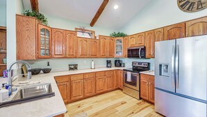 Eine moderne Küche mit Holzschränken, Edelstahlgeräten und einer Marmorarbeitsplatte.