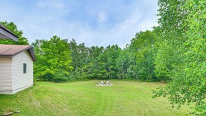 Een huis met een verzorgd gazon en een vuurplaats, omringd door bomen.