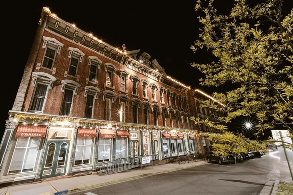 Un edificio histórico con varios locales comerciales, incluyendo un café y un bar, de noche.