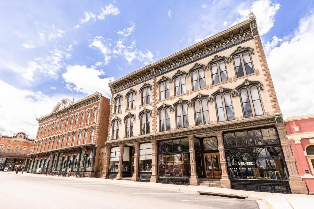 A row of historic buildings with large windows and ornate facades.