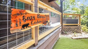 Un panneau en bois représentant un ours et des arbres, indiquant l’emplacement d’un chalet nommé « Easy Bear Cabin ».