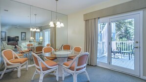 A hotel room with a dining area featuring a round glass table surrounded by wicker chairs, a large mirror, and a balcony with outdoor seating. - 2 Bedroom Villa--Free Golf, Tennis--Pools, Beach and the Fabulous Westin!! (Hilton Head Island)