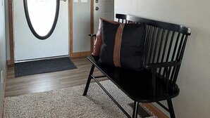 Een receptiezone met een bank, een bord met een welkomstboodschap en een deur met een spiegel.