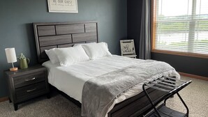 Een slaapkamer met een bed, nachtkastje, lamp en een motiverende tekst.