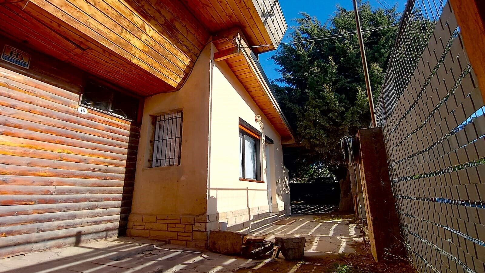 Eine Blockhütte mit Holzfassade und einem kleinen Anbau mit vergitterten Fenstern.