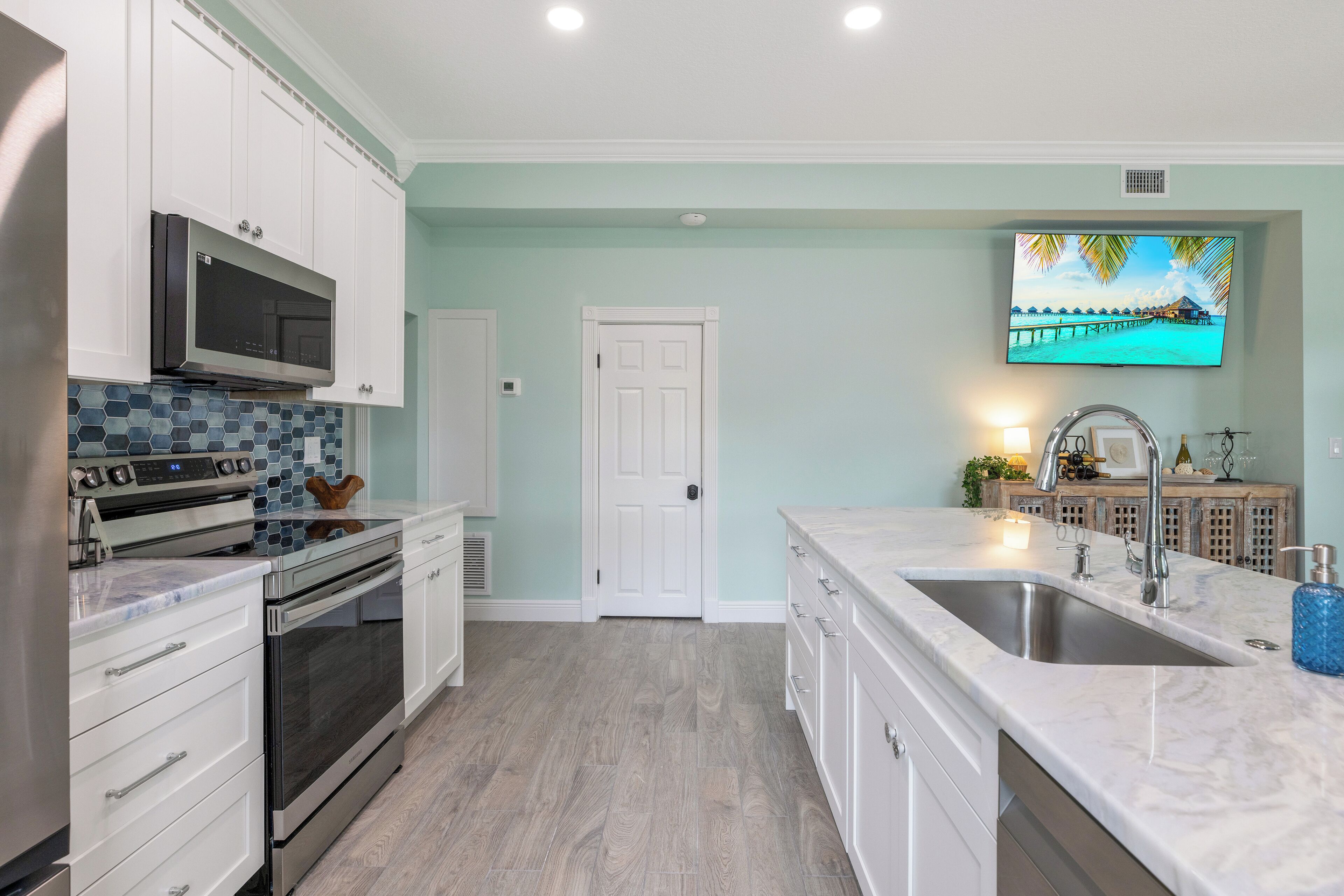 A modern kitchen with white cabinets, a stainless steel refrigerator, a microwave, and a double sink.