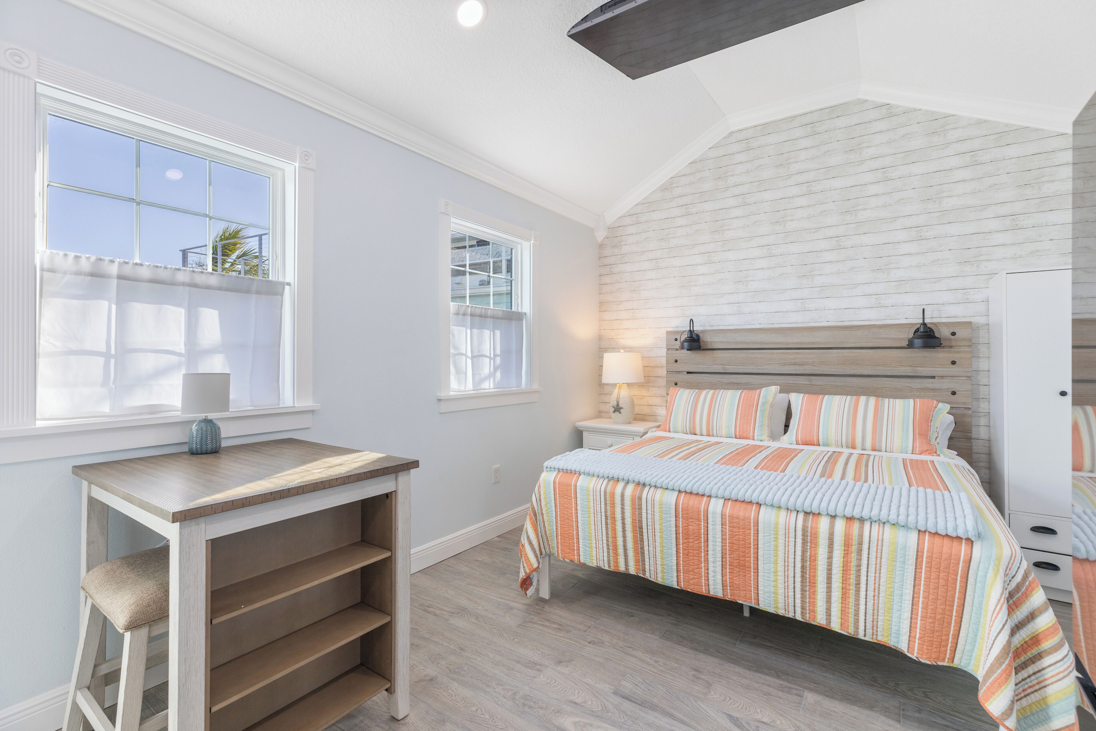 Un dormitorio con cama, escritorio y ventana.