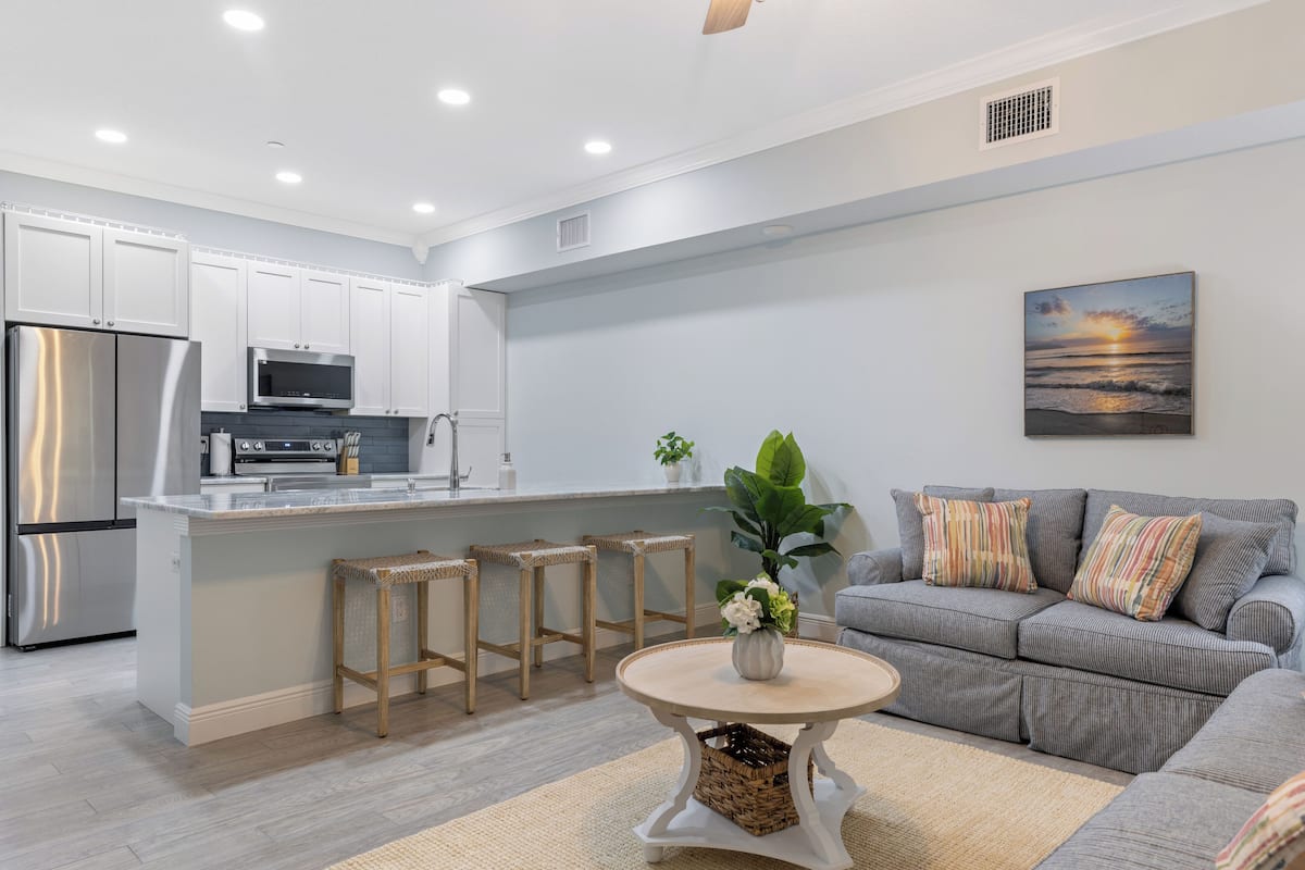 A modern kitchen with white cabinets, stainless steel appliances, and a central island with stools.