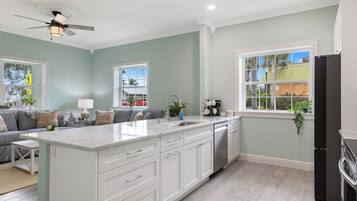 Una cocina moderna con armarios blancos, una isla grande y un lavavajillas integrado.