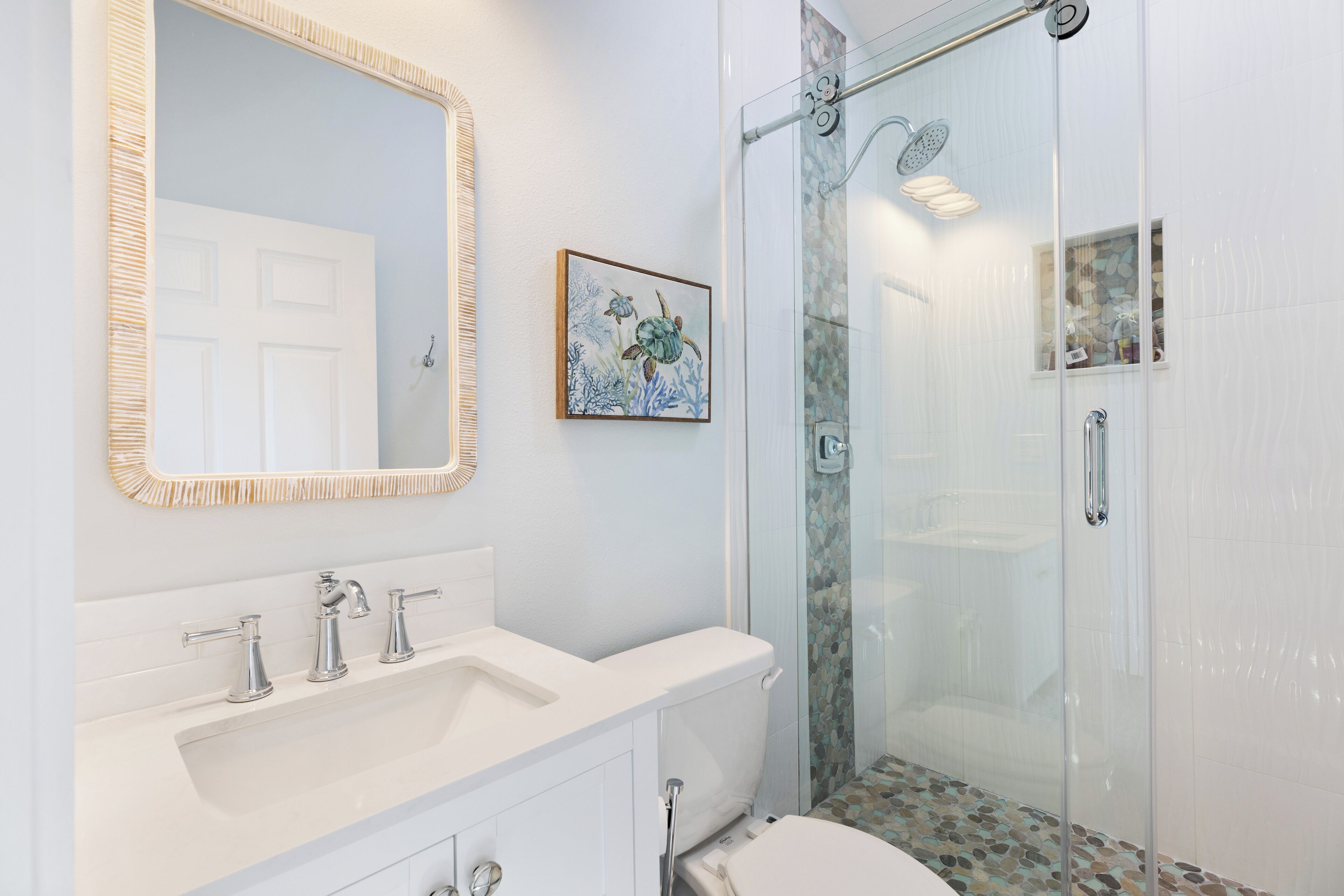 A bathroom with a white sink, mirror, and glass shower enclosure.