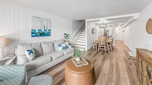 Un salon moderne avec un canapé gris, une table basse et un escalier menant à un espace repas.