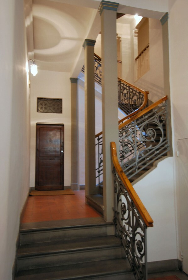Un escalier orné de rampes en métal et doté d’une main courante en bois, menant à l’étage supérieur.