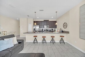 Una cocina moderna con armarios oscuros, encimera de granito y una isla central con taburetes.