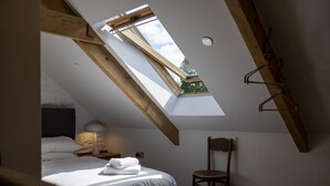 A bedroom with a skylight, a bed, a chair, and a nightstand with a lamp. - Cartws at Pentrecelyn- A Stylish Countryside Haven (Carmarthen)