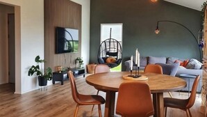 Un salon moderne avec une table à manger ronde en bois, un fauteuil suspendu et un canapé.