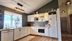 Une cuisine moderne avec des meubles blancs, un four à micro-ondes, un réfrigérateur et un plancher en bois.