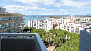 A high-rise building with multiple balconies overlooking a coastal cityscape, including a beach and distant mountains. - APCOSTAS Blue Beach two bedrooms (Salou)