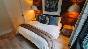 Une chambre à coucher avec une tête de lit en bois, un grand lit avec de nombreux oreillers, deux lampes de chevet et une carte encadrée accrochée au mur.