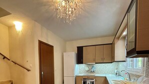 Una cucina moderna con forno integrato, frigorifero e lavandino. Una scala conduce a un altro piano.