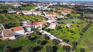 An aerial view of a residential area with houses, green spaces, and a swimming pool. - Casa do Jardim Secreto - Monsaraz (Corval)
