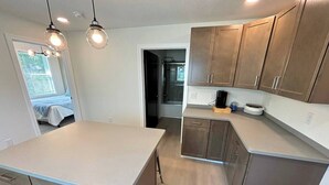 A modern kitchen with a large island, wooden cabinets, and pendant lighting.