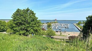A marina with boats docked, surrounded by greenery and a clear sky.