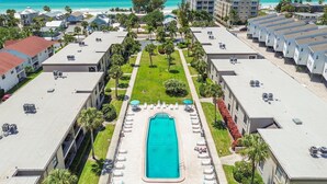 Ein Resort mit einem zentral gelegenen Swimmingpool, mehreren Gebäuden und Blick auf den Strand.
