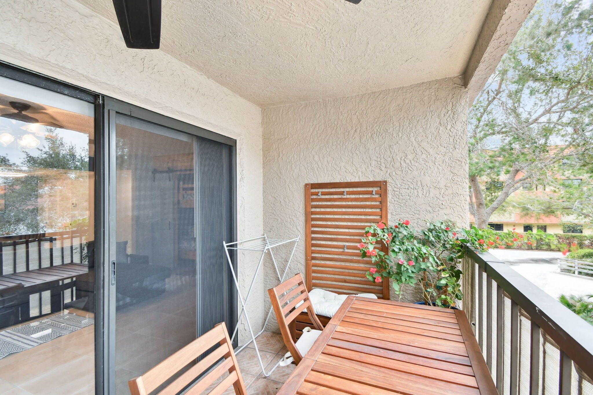 Ein Balkon mit Holztisch und -stühlen, einer Wäscheleine und Blick auf die Umgebung.