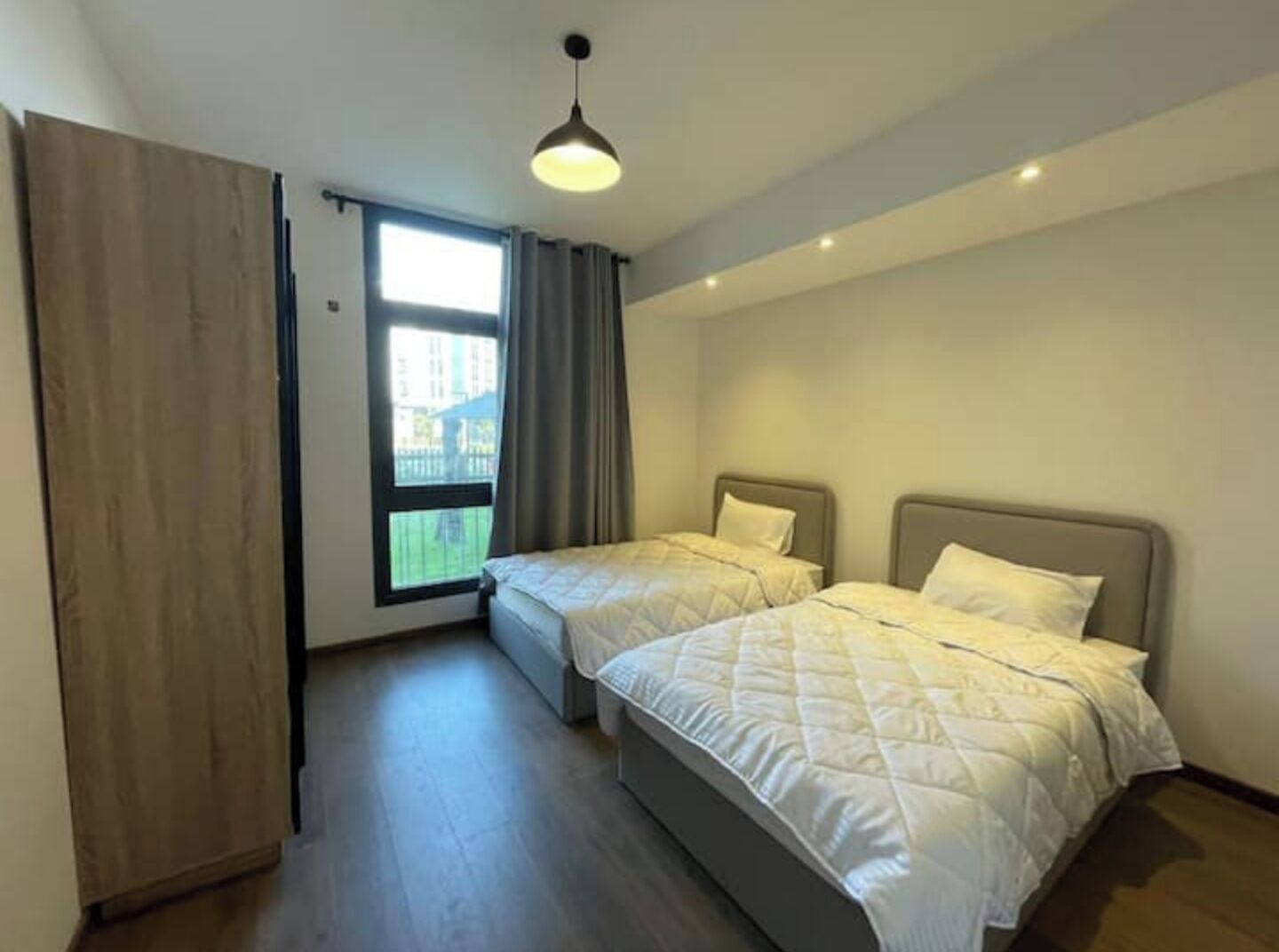 Een slaapkamer met twee bedden, een raam en een plafondlamp.